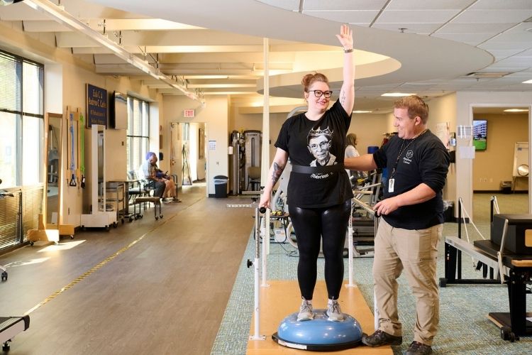Physical Therapist Brian Smith works with Mariah Power on the balance bars and half balance ball to improve her balance and coordination. Balance work can help patients with MS regain function and mobility.